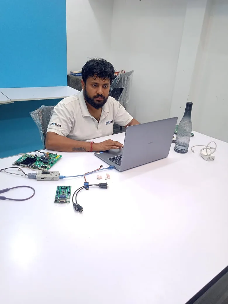An EDIO engineer at a laptop, with SmartClone boards wired up on the desk beside him