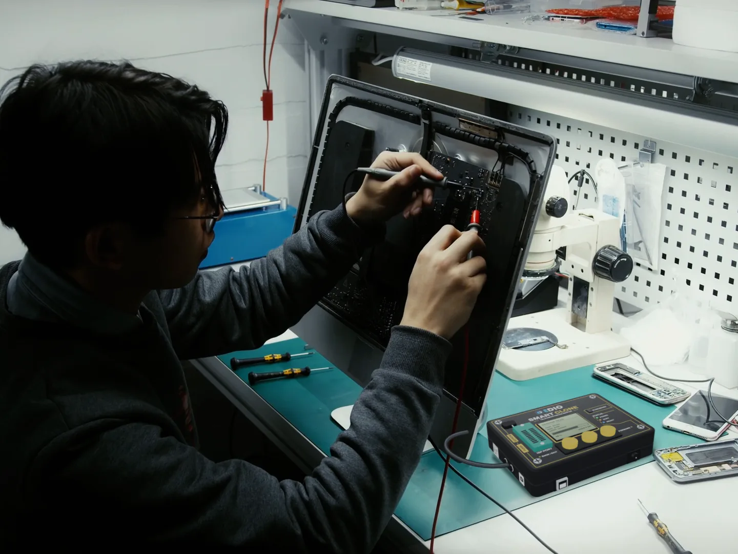 A technician probing a board at his bench, with SmartClone connected beside him