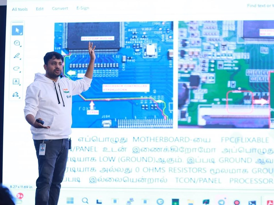 A trainer explaining TV motherboard repair on stage at an EDIO technical training day.