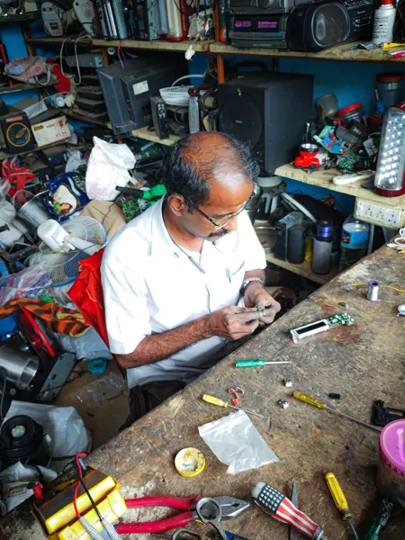 A technician at his bench in a busy electronics repair shop